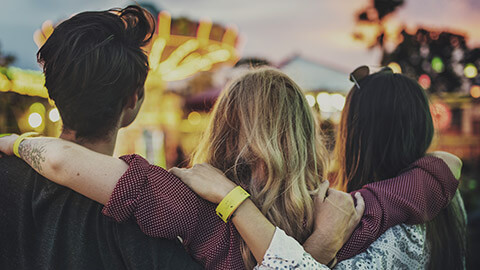 3 friends looking at an amusement park ride that they are about to ride