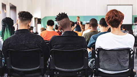 A room of young people listening to a presentation from a youth mentor