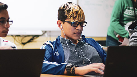 A youth in a classroom learning computer skills