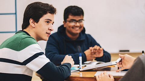 A teacher explaining a project to 2 students