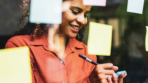 Close view of a women writing on a sticky note to place on a glass window