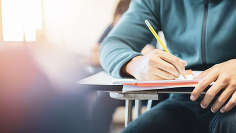 A close view of a student writing in a classroom