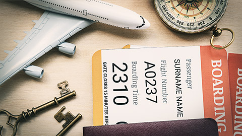 Top view of two boarding pass with passports on a wood floor, decorated with a compass, a white model airplane, brass keys