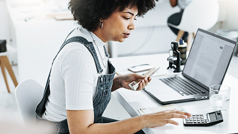 Woman using calculator and laptop