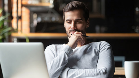 Thoughtful businessman think of online project looking at laptop at workplace