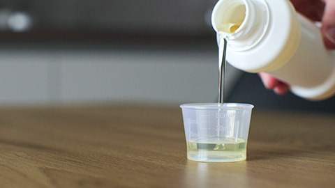 Man pours medical syrup into measuring cap