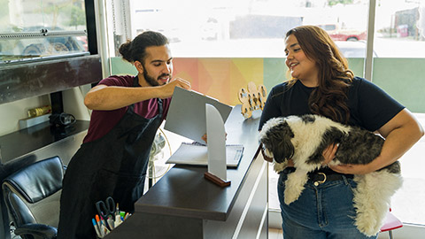 pet groomer giving information of the grooming services to a smiling dog owner