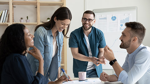 Smiling diverse colleagues gather in boardroom brainstorm discuss financial statistics together