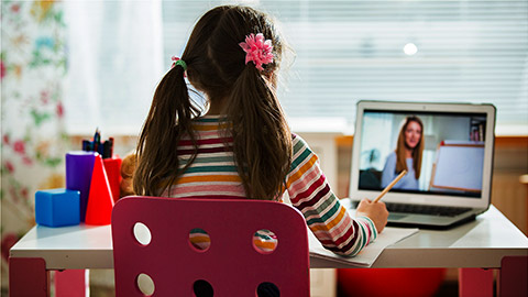 A Child seated at their desk, learning online using a laptop