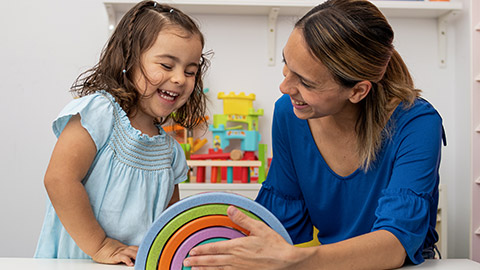 girl and her teacher, playing together in kindergarten