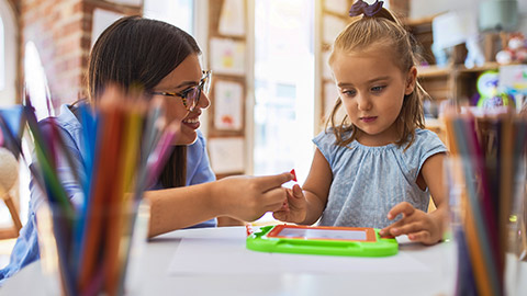 girl kid playing and learning at playschool with female teacher