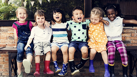 a group of children happily shoulder to shoulder