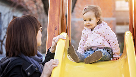 child on slide with supervising adult