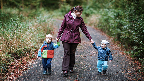 Adult walking with two toddlers outdoor