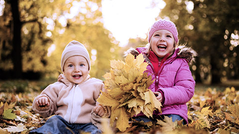 Joyous little girl and her brother in the autumn park