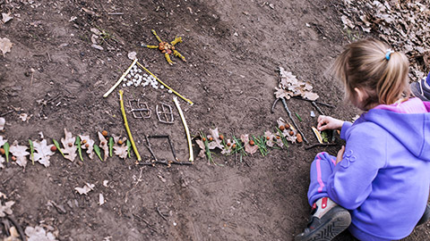 Girl playing outdoor with sticks and leaves