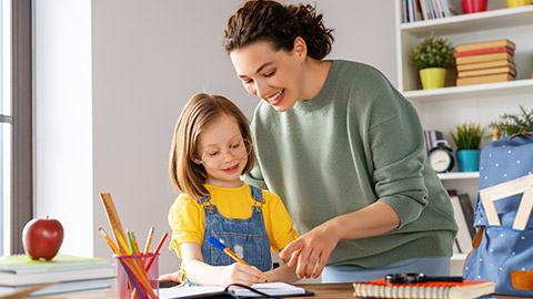 Happy child and adult are sitting at desk