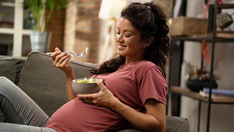 Pregnant woman eating fuit at home