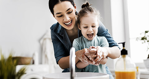 A person teaching child how to brush teeth