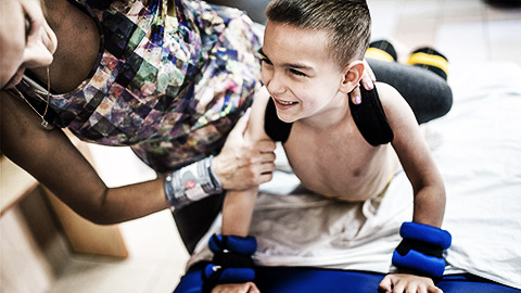 A medical professional assisting a disabled child in an activity