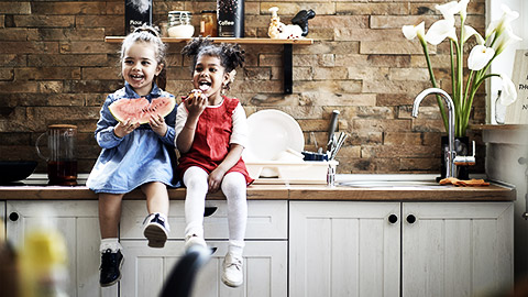 A pair of toddlers eating a watermelon