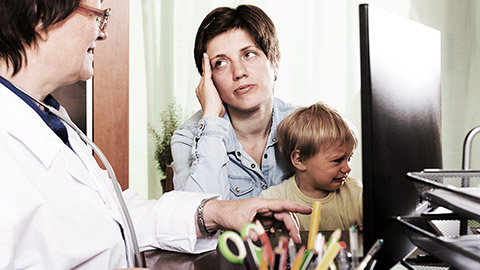 A mom with a crying child talking to a pediatrician