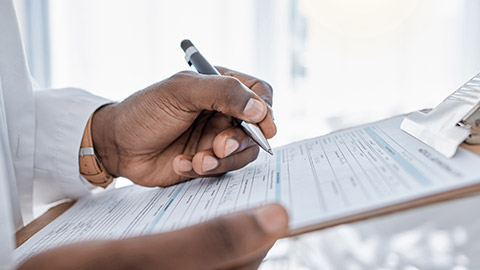 A close view of doctor writing on a clipboard