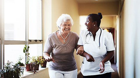 a nurse and an old person interacting in the hallway