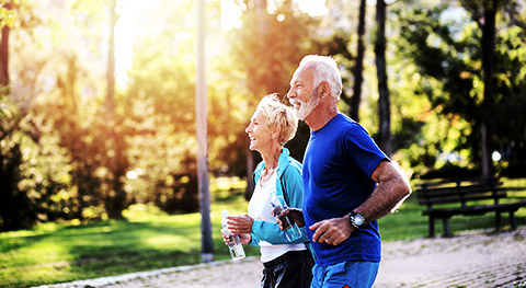 A couple of senior citizens jogging with water in hand