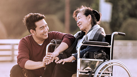 Young manhappily talking with elder on wheelchair