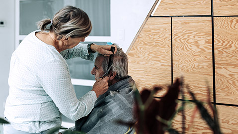 Senior woman hair cutting an elder man