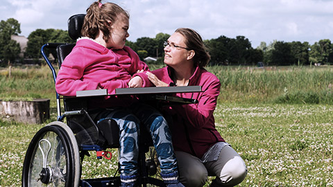 Child on wheelchair talking with a carer