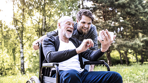 Young man taking selfie with elder on wheelchair