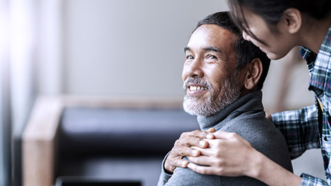 A carer holds the shoulder of an elder man