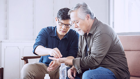 Middle aged man gives medicine to a senior man