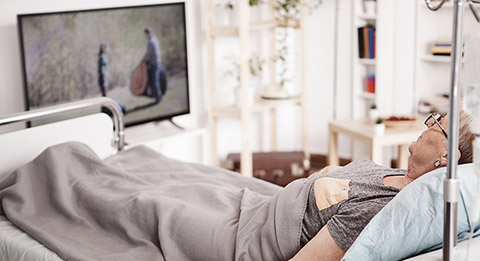 An elderly woman watching TV