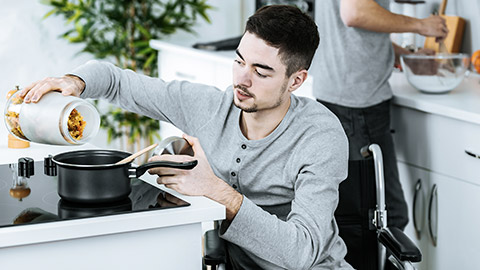 Man on wheelchair cooking with a friend