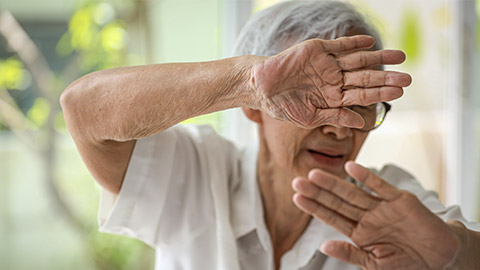 an elderly woman raising hands in defence