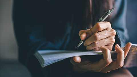 A close view of a person writing in a notebook