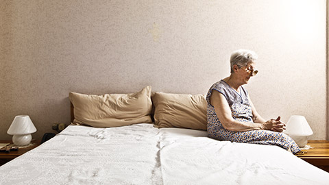 A widow looking lonely while sitting on a bed