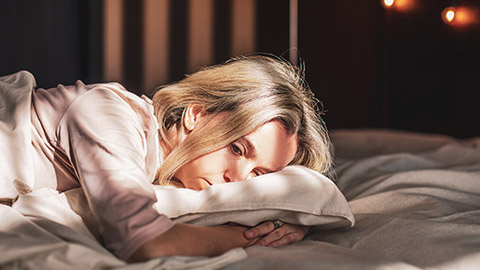 An upset person laying on a bed