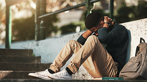 A distraught teenager sitting alone outdoors