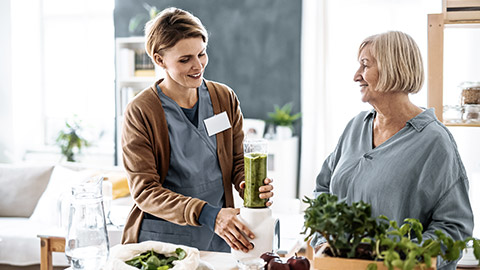 health care worker preparing smoothie for a senior