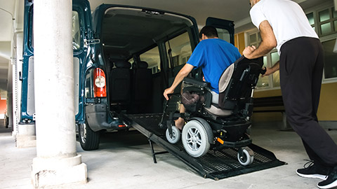 A carer helping a client into a car