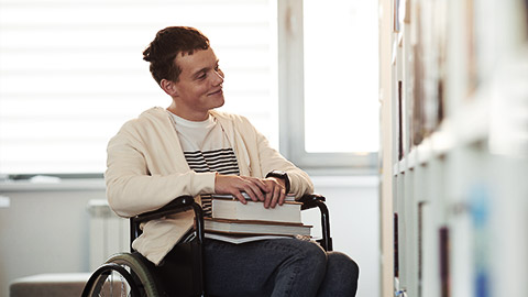 An independent special needs person selecting books in a library