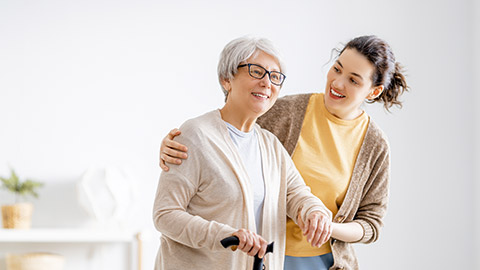 caregiver spending time together with senior woman holding cane