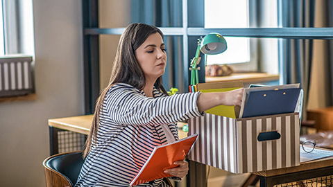 Young woman in a striped jacket sitting on the chair and sorting the files