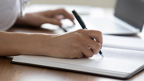 female medical worker handwriting notes in paper book