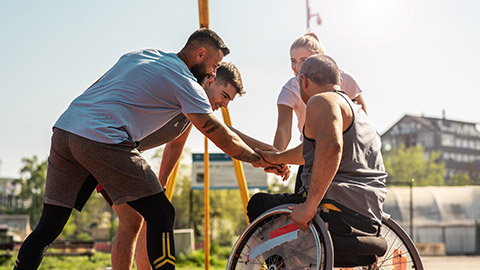 A physically challenged person plays street basketball with his friends.They making high five