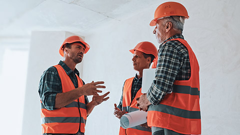 Three workers on a construction site discussing the details of a project